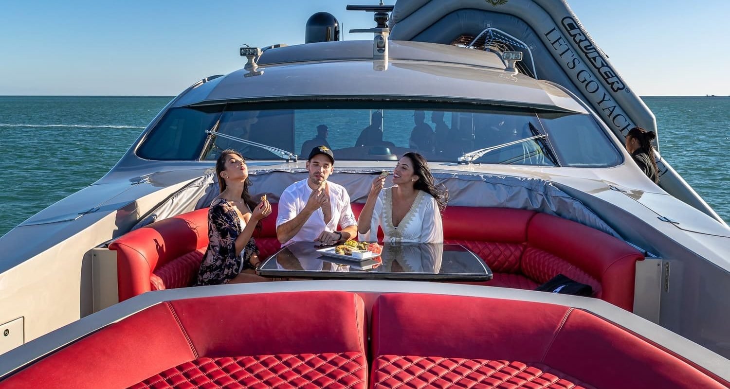 Three people relaxing on the red lounge of the 90' PERSHING REGAL yacht