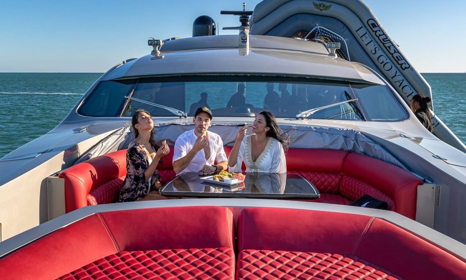 Three people relaxing on the red lounge of the 90' PERSHING REGAL yacht