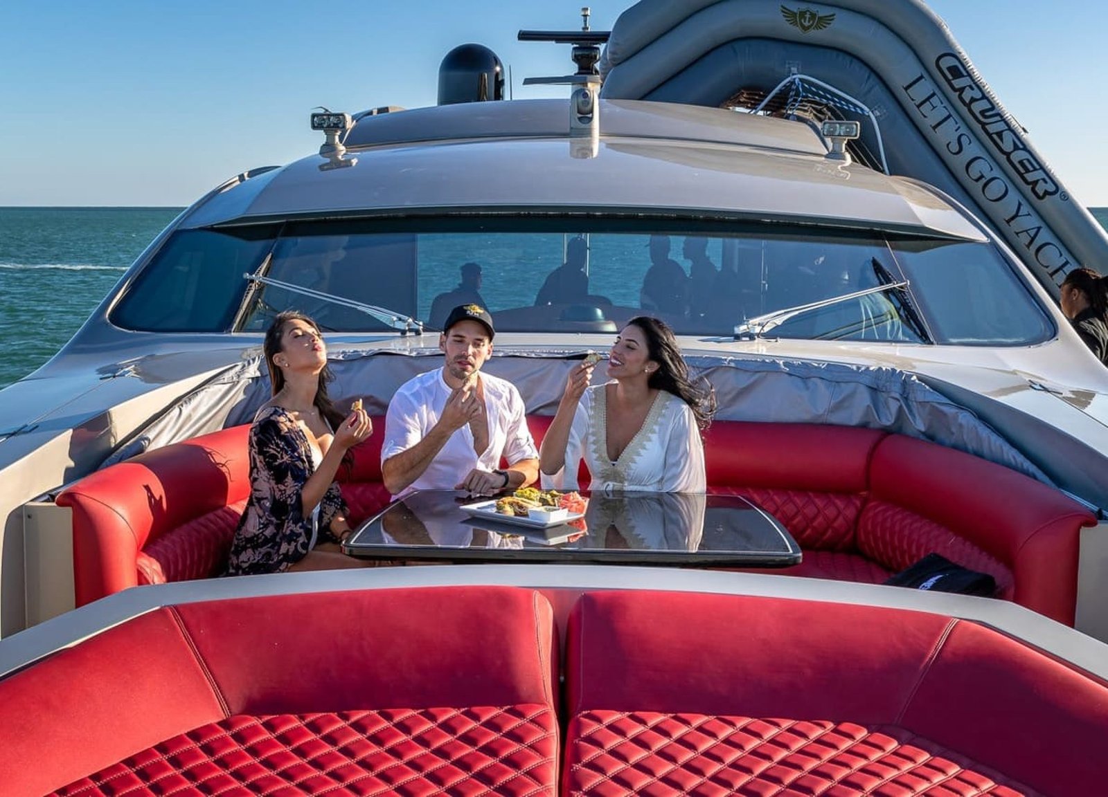 Three people relaxing on the red lounge of the 90' PERSHING REGAL yacht