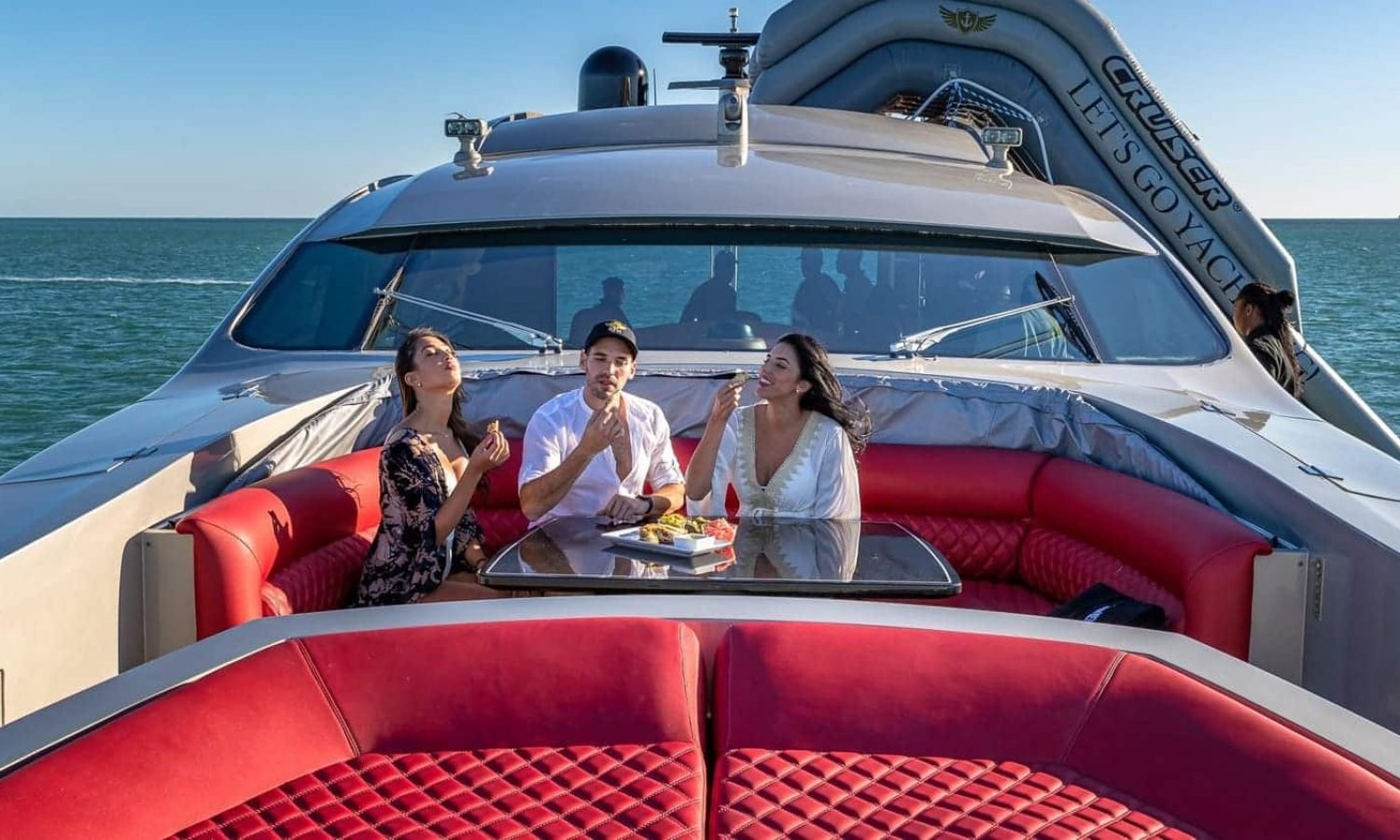 Miami 6 Three people relaxing on the red lounge of the 90' PERSHING REGAL yacht